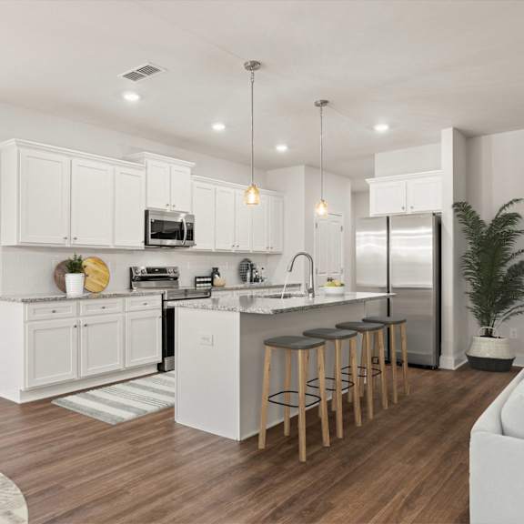 A modern kitchen with white cabinets and a wooden floor.