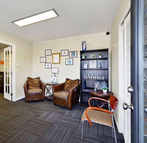 A room with a couch, chairs, and pictures on the wall.