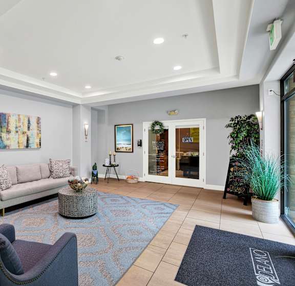 A living room with a couch, chairs, and a painting on the wall.
