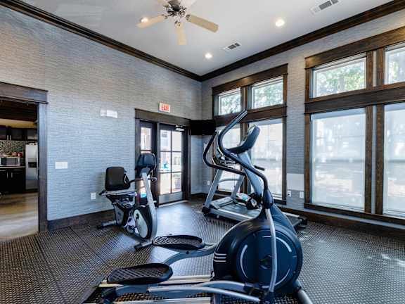 A gym with a row of treadmills and elliptical machines.