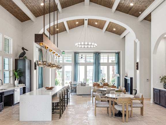 A large open kitchen and dining room with a white island and wooden beams.