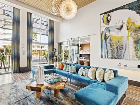 A living room with a blue couch and a large painting on the wall.