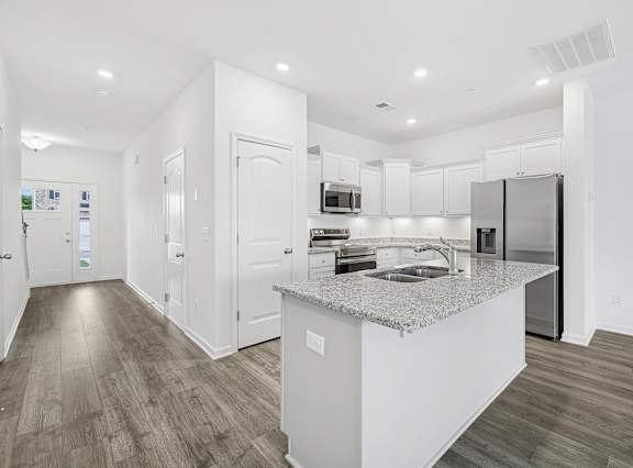 A modern kitchen with a granite countertop and stainless steel appliances.