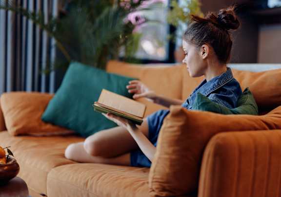 A woman is sitting on a couch reading a book.at Villa Solera, San Jose