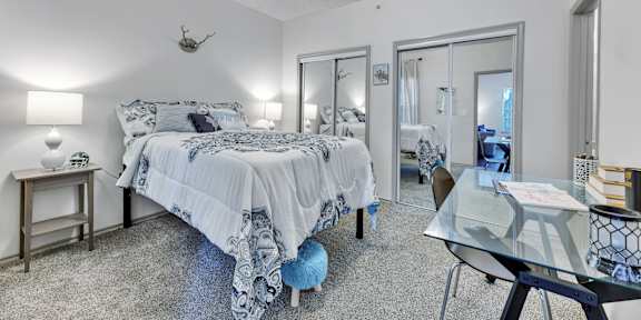 a bedroom with a bed and a glass desk