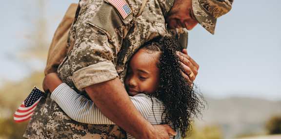 A soldier in camouflage uniform hugging a young girl at Arrowood Farms, Clarksville