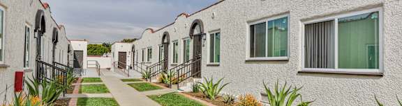 A row of white houses with green plants in front.
