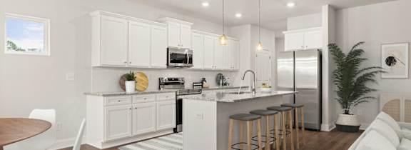 A modern kitchen with white cabinets and a wooden floor.