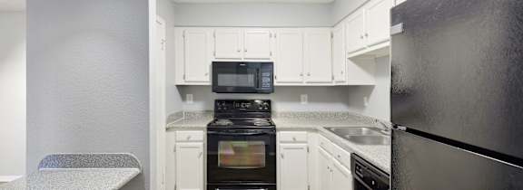 an empty kitchen with black appliances and white cabinets
