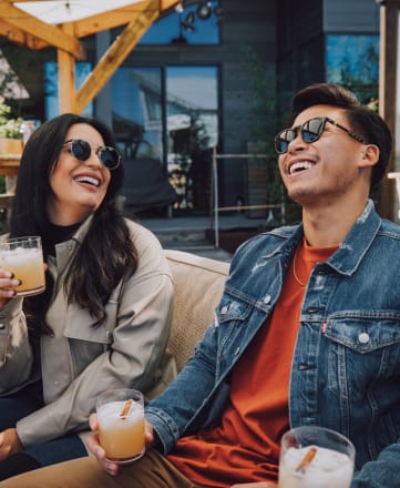 a man and a woman sitting on a couch with drinks in their hands
