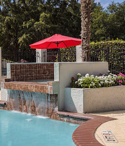 A pool with a red umbrella and a waterfall at The Vistas, Macon, GA, 31210