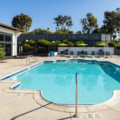 A large outdoor swimming pool with a diving board and lounge chairs.