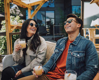 Two people are sitting outside with drinks in their hands.