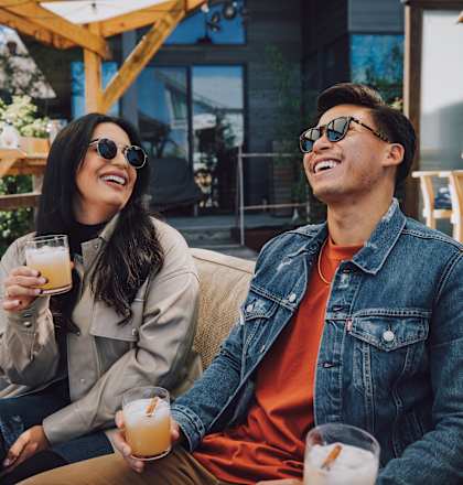 a man and a woman sitting on a couch with drinks in their hands