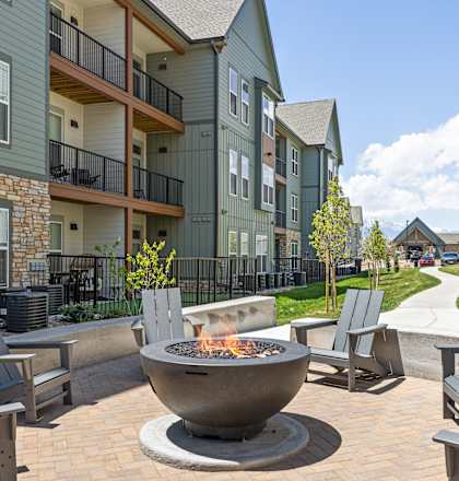 A fire pit sits in the middle of a patio surrounded by chairs. at Upland Flats, Colorado Springs