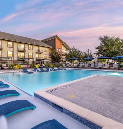 A large outdoor pool with a slide and lounging chairs.