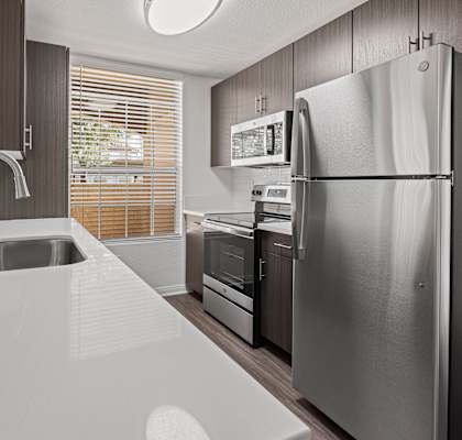 A modern kitchen with a stainless steel refrigerator and a white countertop.