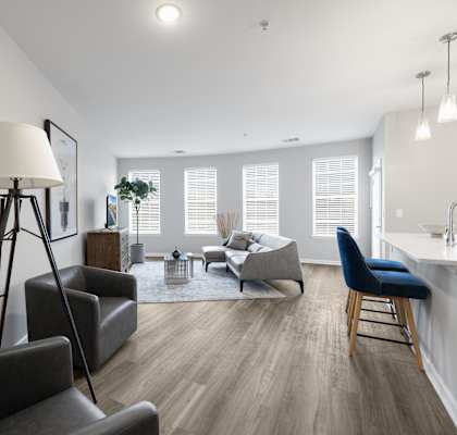 A well-lit, modern living room with a grey sofa, a black chair, and a wooden floor.