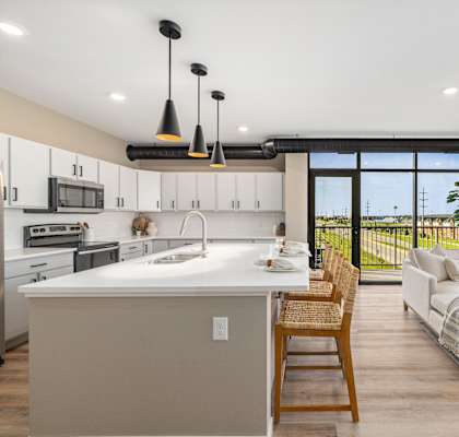 A modern kitchen with a large island and a dining area with a view.