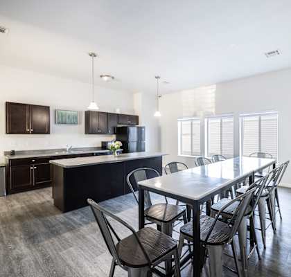 A kitchen with a table and chairs in the foreground and a refrigerator in the background.