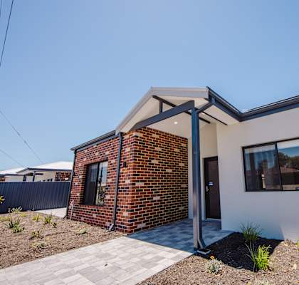A modern house with a brick chimney and a white exterior.