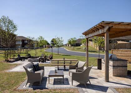 A patio with a table and chairs is surrounded by a grassy area.