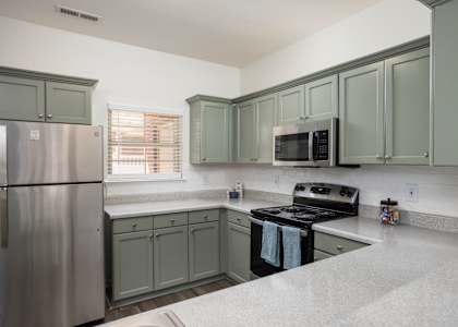A kitchen with a refrigerator, microwave, oven, and cabinets.