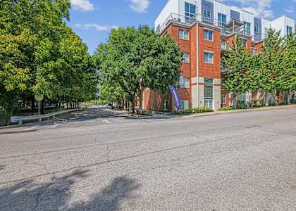 A street view of a residential area with apartment buildings and trees.