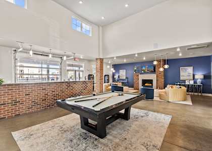 A pool table is in the middle of a room with a brick wall.