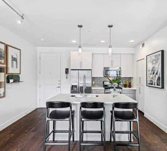 A kitchen with a white table and black chairs.