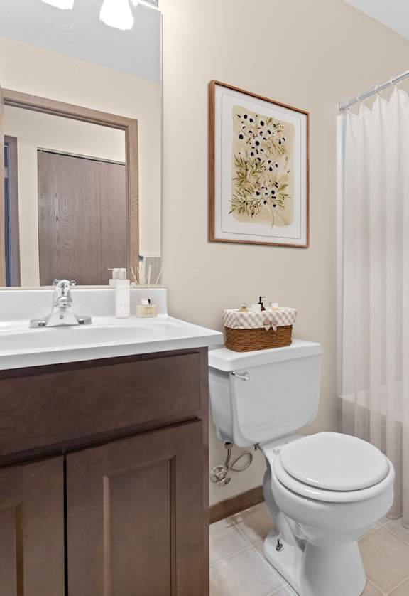 A white toilet sits in a bathroom next to a white sink.