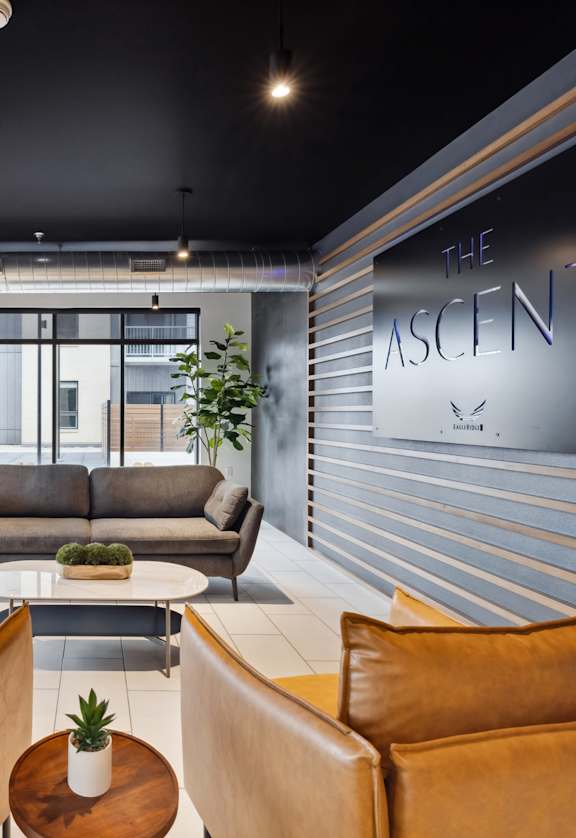 A modern living room with brown leather chairs and a sign that reads "The Ascent".
