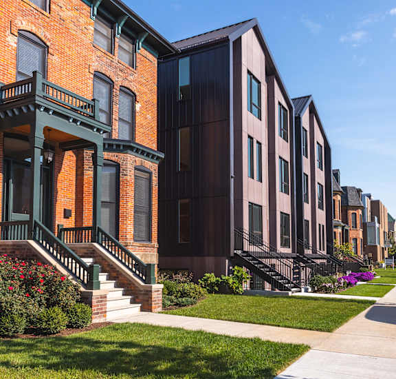 A row of houses with a sidewalk in front.