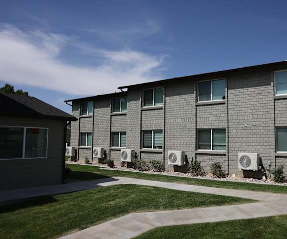 A building with grey walls and multiple air conditioning units in front.