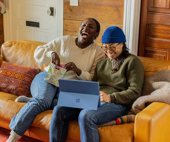 Two people sitting on a couch with a laptop.