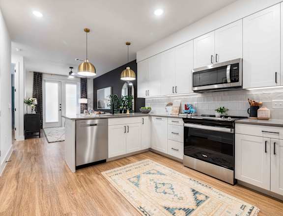 A modern kitchen with white cabinets and a wooden floor.