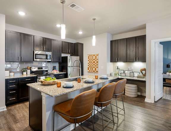 a kitchen with a large island with chairs and a counter top