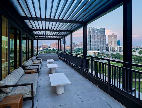 A patio with a black railing and a view of the city.