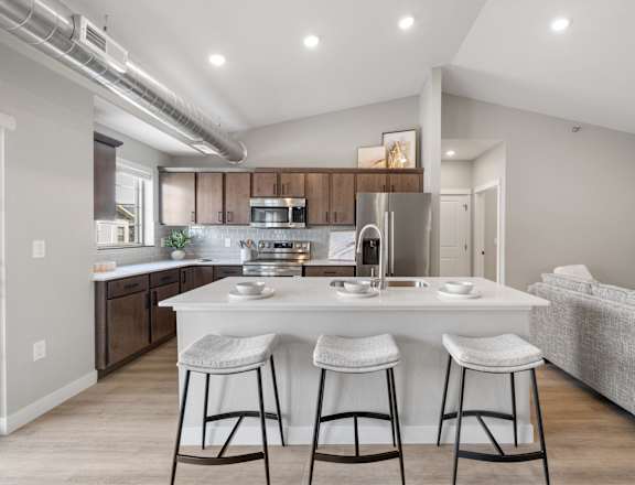 A modern kitchen with a bar stool in front of the island.