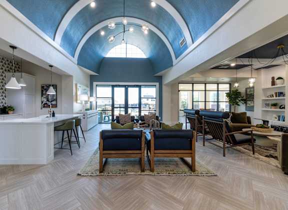 A modern living room with a curved ceiling and a kitchen area.