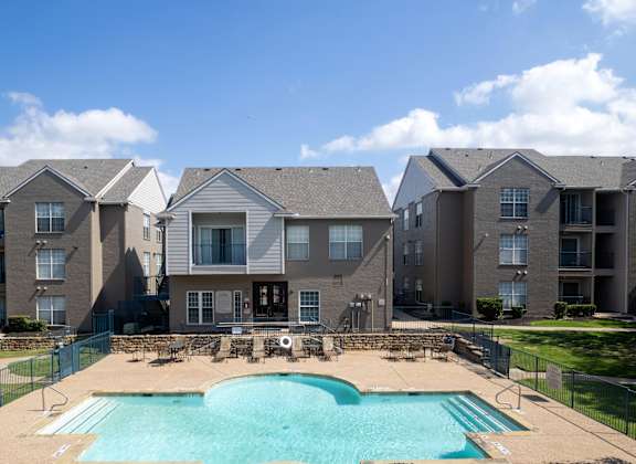 A large swimming pool in front of apartment buildings.