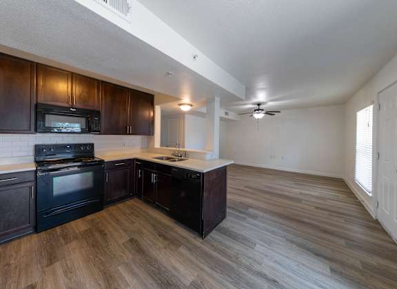 A kitchen with dark wood cabinets and a black stove top oven.