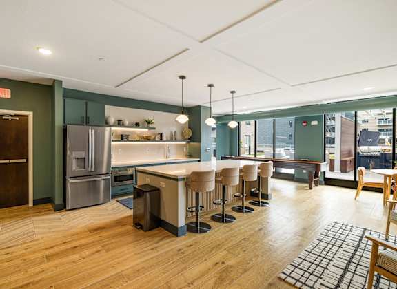 a kitchen with a large island with bar stools and a stainless steel refrigerator at EagleRidge Plaza Residences, Fargo, 58104