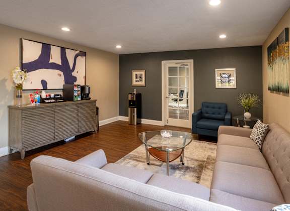 A living room with a white couch and a glass coffee table.