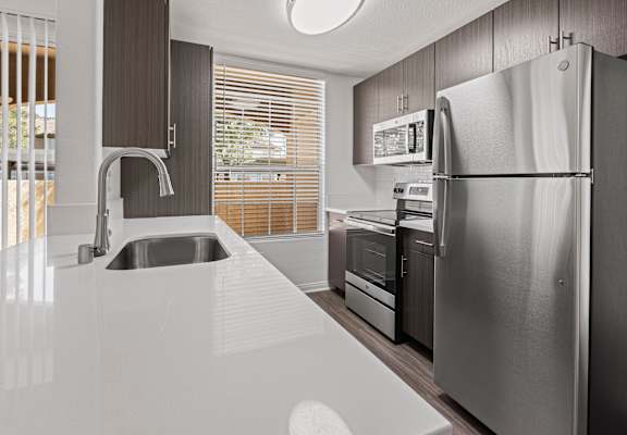 A modern kitchen with a stainless steel refrigerator and a white countertop.