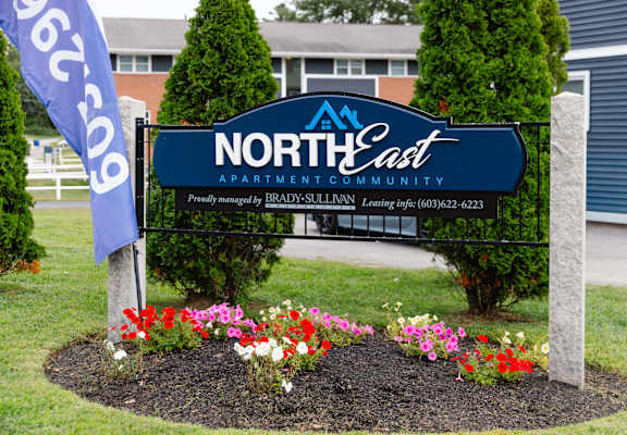 A sign for North East Apartment Community with a phone number on it.