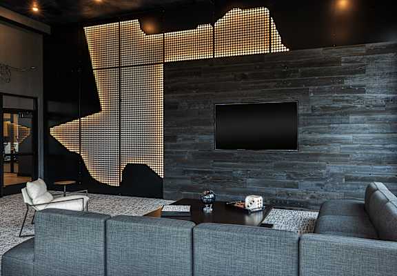 A modern living room with a grey couch and a flat screen TV mounted on a stone wall.
