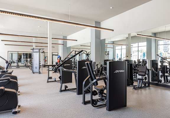 A gym with a variety of equipment including treadmills, weights, and exercise machines.