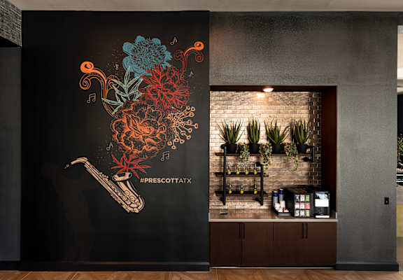 A wall with a drawing of a saxophone and flowers with the hashtag #prescottaxx.