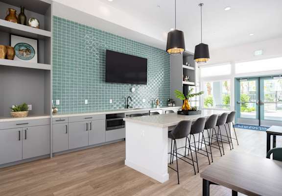 A modern kitchen with a white island and grey cabinets.